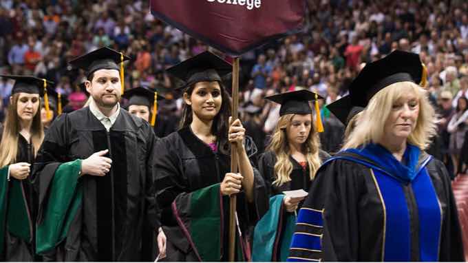 Graduate students in cap and gown being led into commencement ceremony