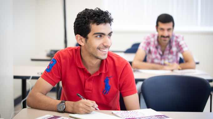 Two students sitting in a classroom, smiling