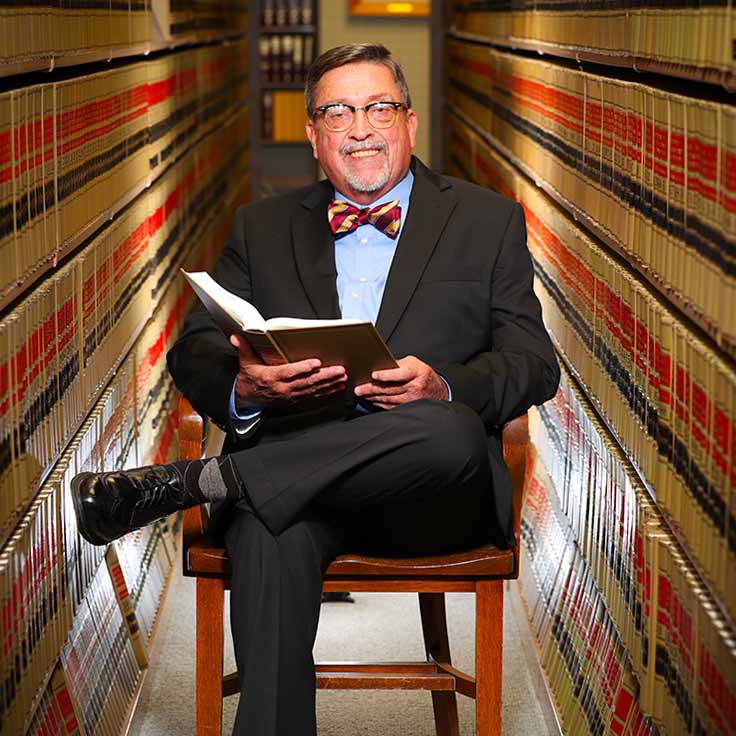 Dr. Stanley Leasure sitting, holding a book